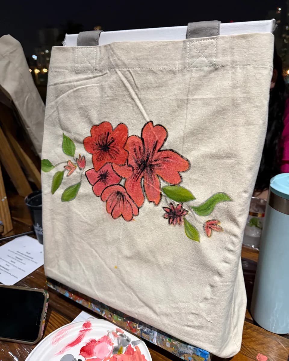 Tote bag de lona pintada a mano con hibiscos rojos sobre un caballete