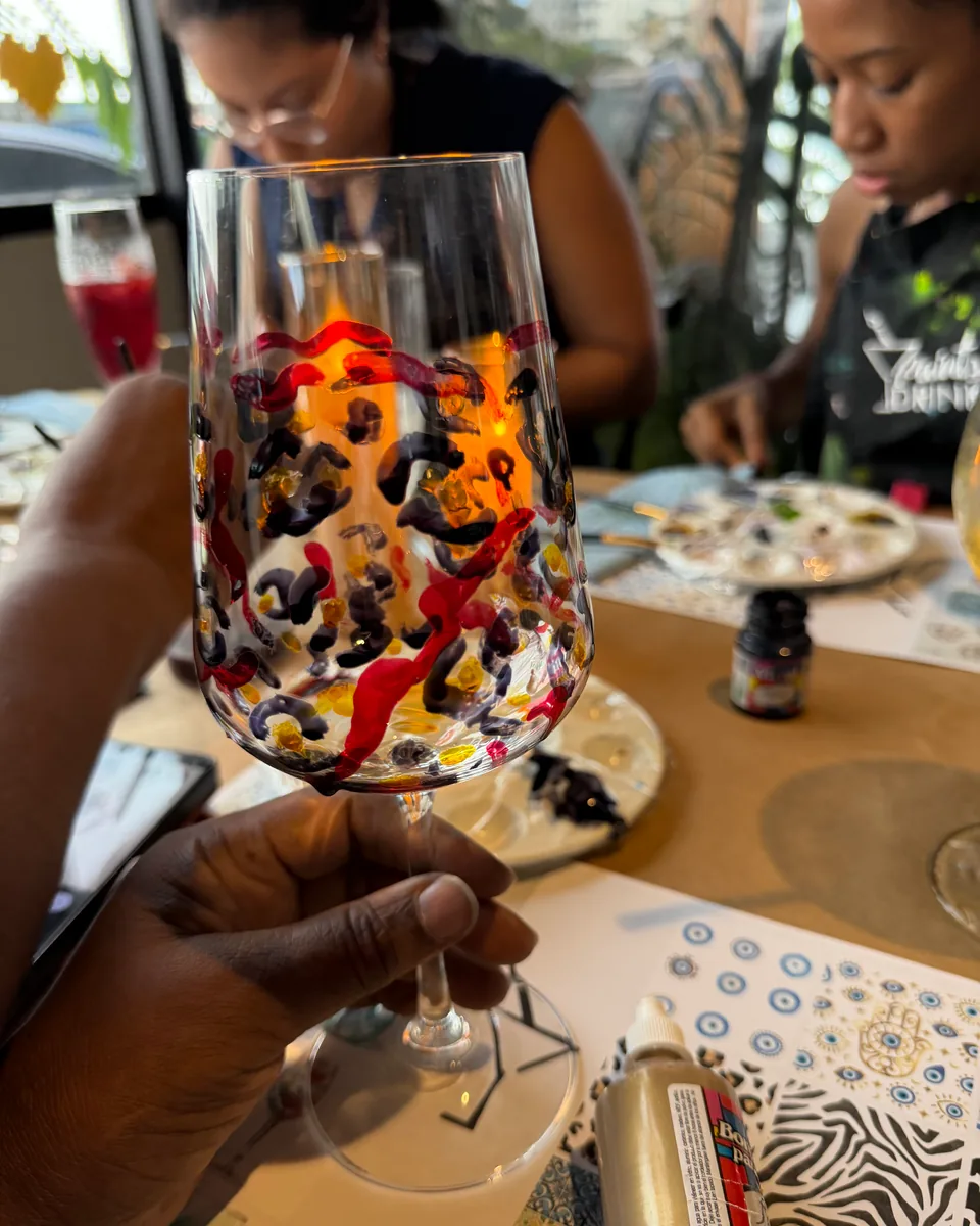 Copa de vino pintada a mano con trazos rojos, negros y dorados en una sesión de Pinta tu Copa